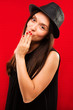 © veles_studio - Young pretty woman, with long dark hair, wearing on hat and black blouse, looking at camera and having fun