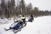 Woman And A Man Driving Snowmobile In Ruka Of Lapland