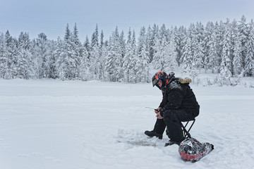 Wall Mural - Man is ice-fishing in Ruka in Lapland