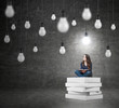 © ImageFlow - woman sitting on a pile of books thinking about problem