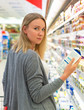 © M-Production - Woman choosing milk in grocery store.