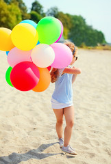 Wall Mural - Little girl child with colorful balloons walking on beach