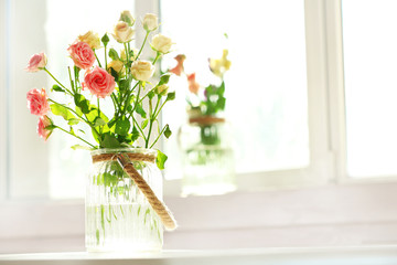 Beautiful spring flowers in vase on window background