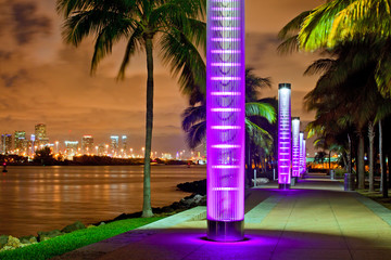 Wall Mural - Miami BEach Florida at night, South Pointe park colorful lights and pedestrian path by the ocean and panorama of downtown in the background. Famous tourist destination.