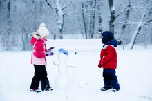 Little Boy And Girl Molding A Snowman
