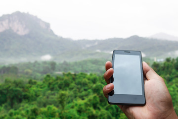 hand hold and touch screen smart phone, tablet,cellphone on nature blurred background.with green blurred nature background.