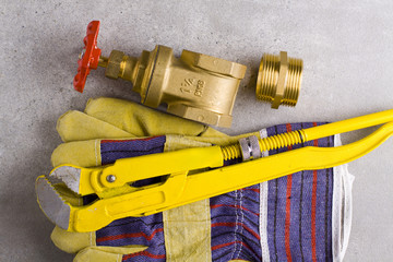 Poster - Wrench, working gloves and brass fittings on crude floor background. 