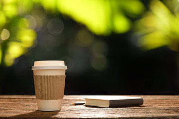 Wall Mural - Paper cup of coffee and book in the garden