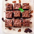  Brownie pieces with nuts on the white paper decorated with mint leaves.