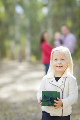 Wall Mural - Baby Girl With Christmas Gift Outdoors Parents Behind