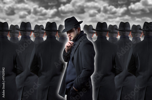 Fotografering Mysterious man making a silence gesture while standing out from the crowd