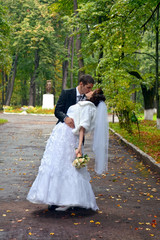 Wall Mural - Happy wedding couple. Bride and Groom kissing in the park 