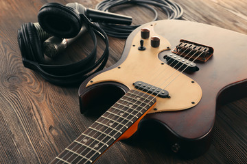 Canvas Print - Electric guitar with microphones and headphones on wooden table close up