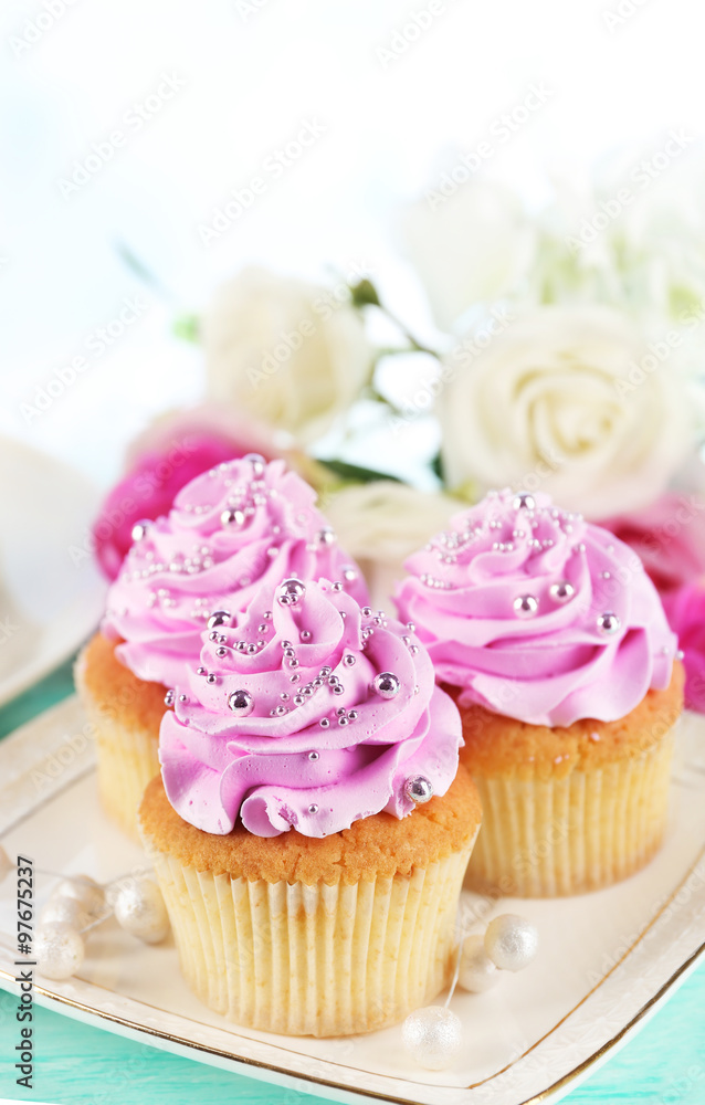 Tasty cupcakes on plate, on color wooden background