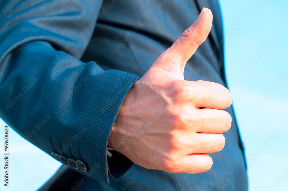A man in a suit hand gesturing thumbs up