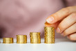 © vladstar - Female hand stacking gold coins into increasing columns