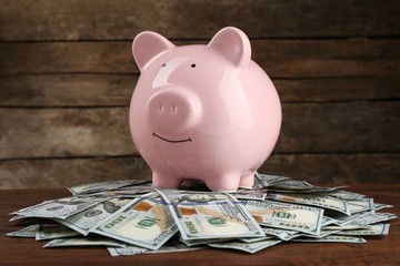 Wall Mural - Pig money box and dollar banknotes on wooden wall background