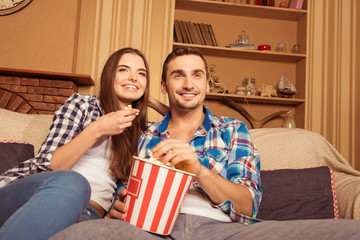 Sticker - Young couple in love with popcorn on the sofa watching a movie