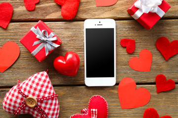 Wall Mural - Smart phone with blank screen and hearts on old wooden table