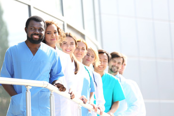 smiling medics team standing in a row near the clinic