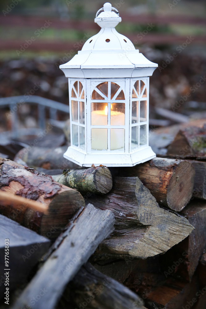 Lantern with candle on stack of firewood
