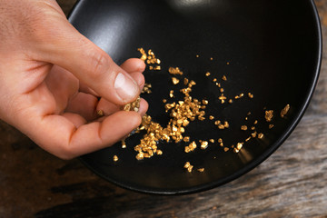 A hand holding gold nugget grains, close-up