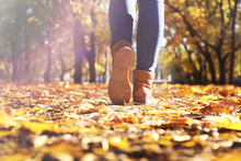 Female Legs In Boots On Autumn Leaves