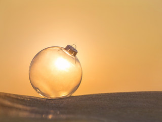 Canvas Print - Christmas-tree decoration transparent glass ball at sunset beach