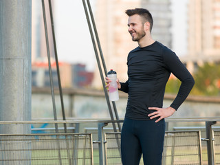 Young handsome man running along the embankment near the river u