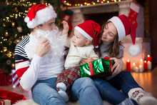 Surprised Child Looks At Dad Weared Santa Claus With Fake Beard Sitting Opposite Christmas Tree