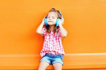 Happy smiling child enjoys listens to music in headphones over c