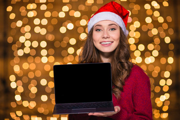 Poster - Beautiful woman in santa claus hat showing laptop blank screen