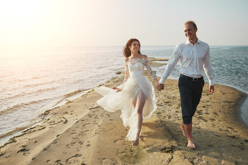 Just married couple running on a sandy beach