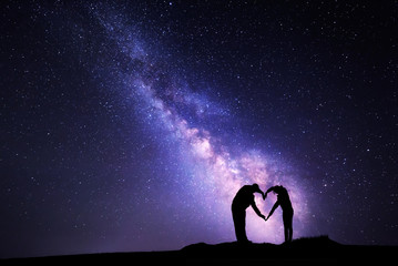 Wall Mural - milky way. man and woman holding hands in heart shape