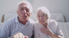 Cheerful senior couple having a skype conversation at home