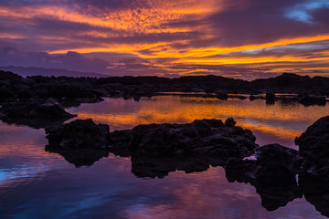 Sunset at Shark's Cove Beach with rocky shore