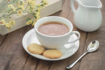 Coffee cup with cookies and book on wooden table