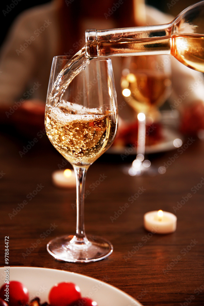 Pouring white wine from bottle into the wineglass
