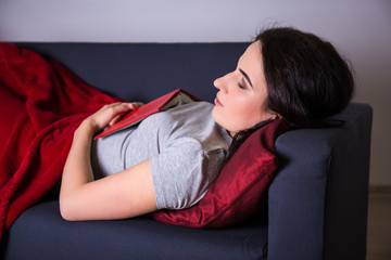 Wall Mural - young woman sleeping with book on sofa at home