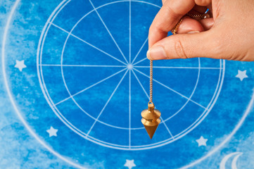 Wall Mural - hand holding a pendulum against an astrological background