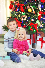 Funny kids with gift boxes and Christmas tree on background