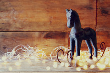 Double Exposure Image Of Rocking Horse And Magic Christmas Lights On Wooden Table