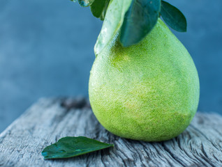 Wall Mural - Pomelo with green leaves on a wooden board