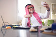 © Mediteraneo - Arabian business man in his home office using smart phone