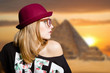Charming girl in hipster glasses on Egypt pyramid blurred background
