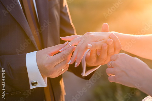 Fotografie, Obraz Groom slipping ring on finger of bride at wedding