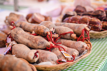 Picture of fresh meat sausages with red strings on tabletop. Spicy delicatessen on blurred market indoor background