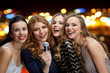 © Syda Productions - happy women with microphone singing over lights