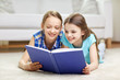 © Syda Productions - two happy girls reading book at home