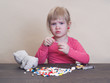 Маленький ребенок играет с лекарствами. Много разноцветных таблеток. Опасность, яд! Плохие игры для маленьких детей.  